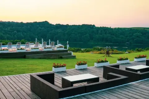 Idealne mazury na weekend: taras z meblami, basen z leżakami i jezioro w tle.