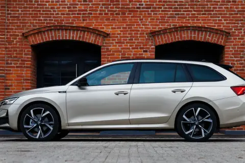 Złoty kombi Octavia 4 stoi na tle ceglanej ściany z dwoma łukowatymi oknami.