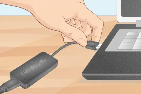 Dłoń podłącza kabel karty przechwytującej do laptopa.
