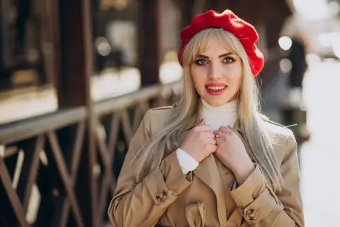 Kobieta w czerwonym beretcie i beżowym płaszczu, jakby prosto z pokazu francuskich projektantów mody.