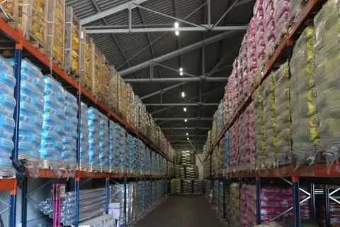 Magazyn Atex Pilchowice z ekogroszkiem i innymi produktami na paletach. Rzędy worków w foliowych opakowaniach.