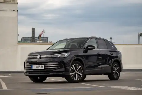 Czarny VW Tiguan Allspace na parkingu pod chmurką. Elegancki SUV z chromowanymi detalami i nowoczesnymi felgami.