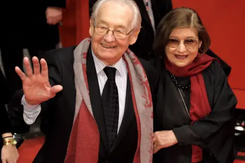 Andrzej Wajda z żoną, Krystyną Zachwatowicz, na czerwonym dywanie. Uśmiechnięci, elegancko ubrani, pozdrawiają publiczność.
