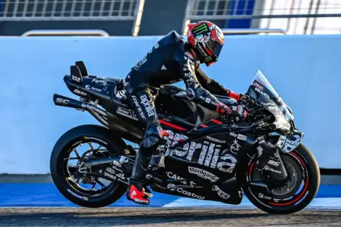 Marco Bezzecchi in voller Fahrt bei einem MotoGP-Rennen. Sein schwarzer Anzug und das Motorrad sind mit Sponsorenlogos bedeckt.