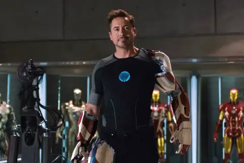 Tony Stark, czyli Iron Man, w swojej zbrojowni, otoczony przez kilka swoich pancerzy.