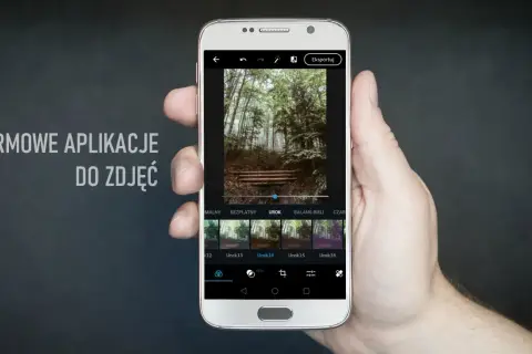 Dłoń trzyma smartfon z aplikacją do edycji zdjęć. Na ekranie widać leśny krajobraz i dostępne filtry, idealne dla fotografów szukających darmowych aplikacji.