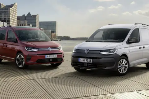 Dwa Volkswageny Caddy 3: czerwony osobowy i biały dostawczy, stoją na tle nowoczesnej architektury i wody.