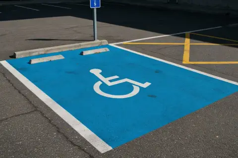 Niebieskie miejsce parkingowe dla niepełnosprawnych, oznaczone symbolem wózka, jest częścią wspólnoty dbającej o dostępność.