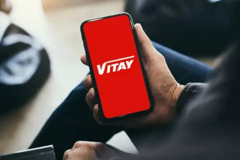 Dłoń trzyma smartfon z czerwoną kartą VITAY.