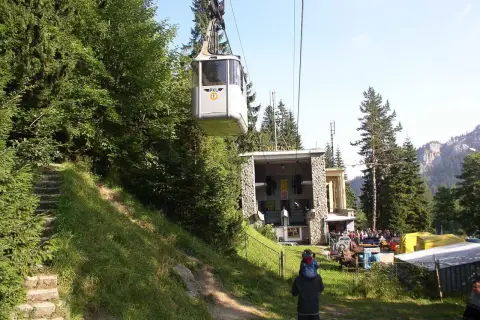 Kolejka linowa PKL wjeżdża na stację w Kuźnicach. W tle góry i las.