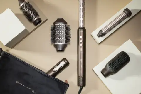 Herramientas para un blow out hair perfecto: cepillos redondos, un rizador y un cepillo plano, junto a un estuche.