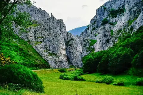 Majestuosas rocas flanquean un valle verde, donde la **cascada de Mazobre** se esconde entre la vegetación exuberante.