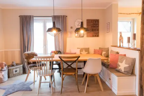 Gemütliches Esszimmer gestalten: Holztisch, Bank mit Kissen, verschiedene Stühle und Wanddeko schaffen einladendes Ambiente.