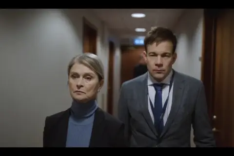 Malte Ekblom går med en kvinna i en korridor.