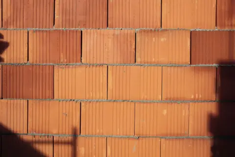 Ściana z cegieł POROTHERM w zbliżeniu. Widoczne poziome spoiny zaprawy i pionowe kanaliki w cegłach.