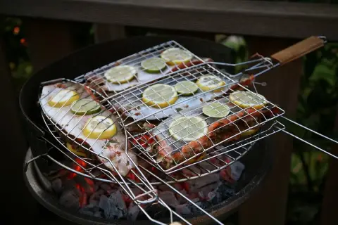 Grilla abborre med citron och lime på en kolgrill. Doften sprider sig i sommarkvällen.