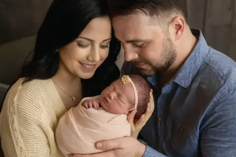 Ciepłe sesje noworodkowe z rodzicami. Mama i tata z czułością tulą swoje maleństwo, tworząc niezapomniane wspomnienia.