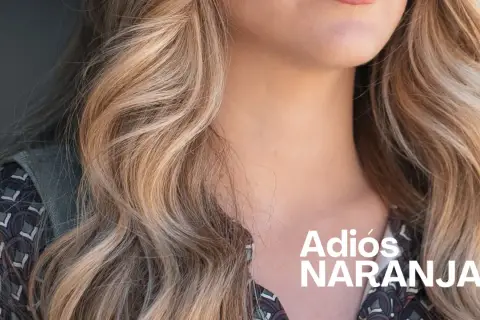 Cabello rubio con mechas matizadas, luciendo un estilo fresco y vibrante. "Adiós Naranjas" en texto blanco.