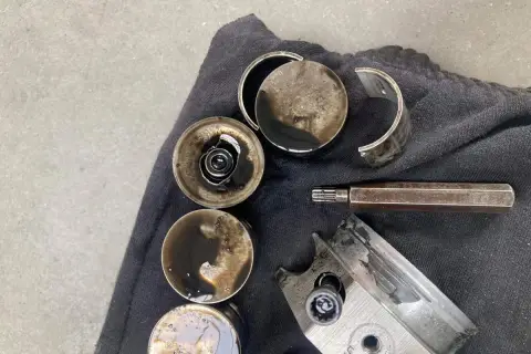 Zużyte popychacze hydrauliczne i fragmenty metalu z olejem silnikowym.