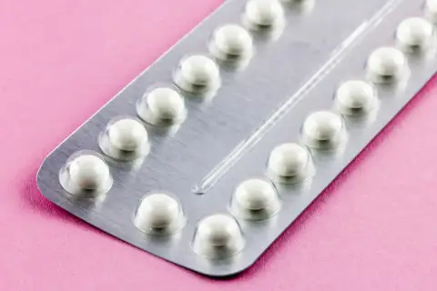 Eine Blisterpackung mit weißen Pillen auf rosa Untergrund. Die Pillen sind bereit, um sie durchzunehmen.