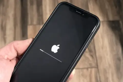 iPhone z logo Apple i paskiem postępu, aktualizacja iOS 26.3 w toku.