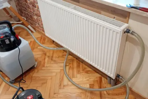 Profesjonalne płukanie instalacji grzewczej w Warszawie. Sprzęt do czyszczenia podłączony do grzejnika.