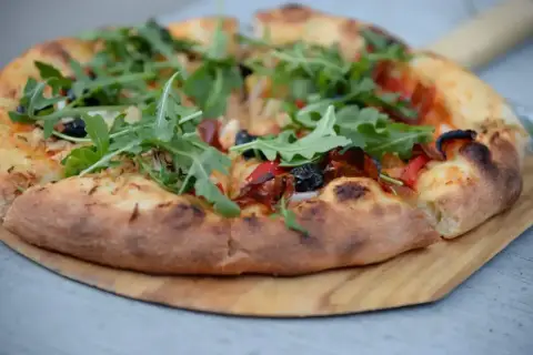 Pyszna pizza domowa na blachę, z ciasta na świeże drożdże, z rukolą i oliwkami.