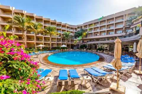 Basen hotelowy Beau Rivage z leżakami i palmami, otoczony budynkami hotelowymi.