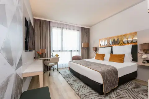 Nowoczesny pokój hotelowy z dużym łóżkiem, biurkiem i telewizorem.