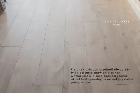 Jasne panele podłogowe ułożone równolegle do okna.