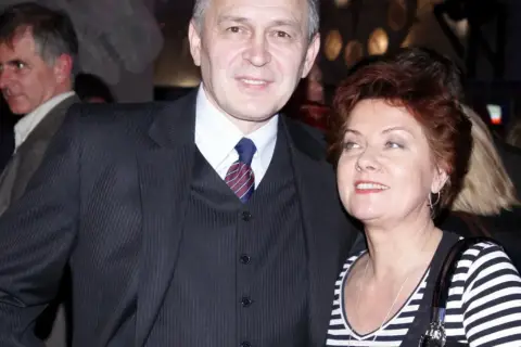Jacek Sas Uhrynowski w garniturze i kobieta w pasiastym topie.