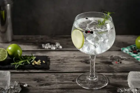 Szklanka z ginem i tonikiem, lodem, plasterkiem limonki, rozmarynem i pieprzem.