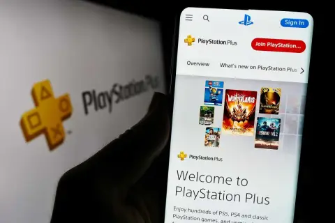 Gry co miesiąc PS Plus na ekranie telefonu, obok logo PlayStation Plus.