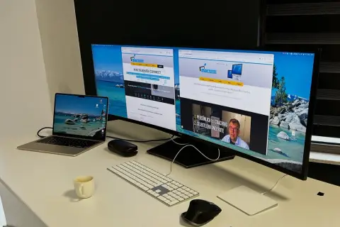 Ein Arbeitsplatz mit mehreren Bildschirmen eingerichtet. Ein Laptop, eine Tastatur, Mäuse und eine Kaffeetasse stehen auf dem Schreibtisch.