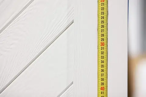 Miarka przy białej, drewnianej ścianie. Wskazuje 30 cm. Pytanie: jaki otwór pod drzwi przesuwne 80?