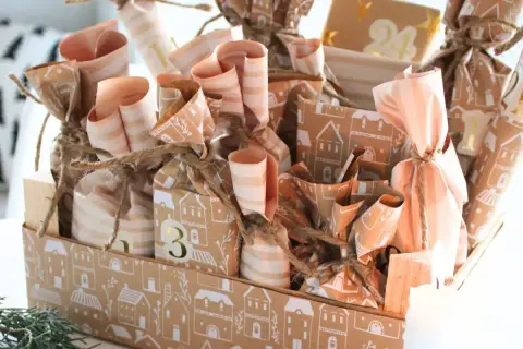 Ein liebevoll gestalteter Adventskalender mit vielen kleinen Päckchen, die mit Häusern und Streifen verziert sind. Tolle Adventskalender Gutscheine Ideen für jeden Tag.