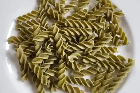 Zielony makaron fusilli z zielonego groszku, ułożony na białym talerzu. Idealny do lekkiego i zdrowego posiłku.