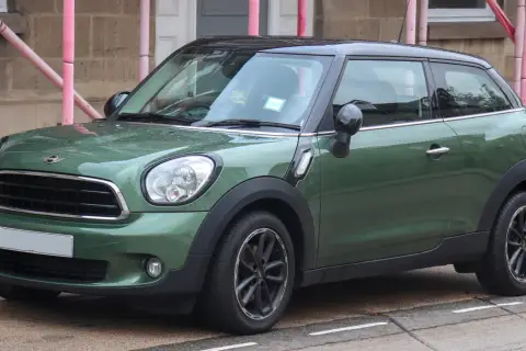 Zielony mini paceman stoi na ulicy, mokry od deszczu.