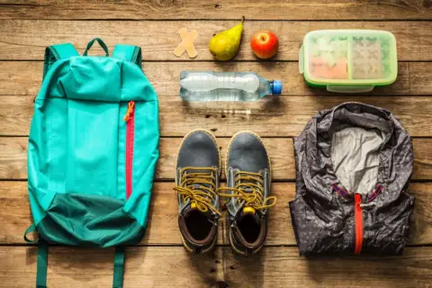 Rucksack, Schuhe, Jacke, Wasserflasche, Obst und Lunchbox – alles für die Klassenfahrt Packliste bereit.