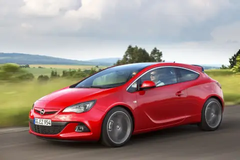 Czerwony Opel Astra Turbo pędzi przez malownicze krajobrazy.