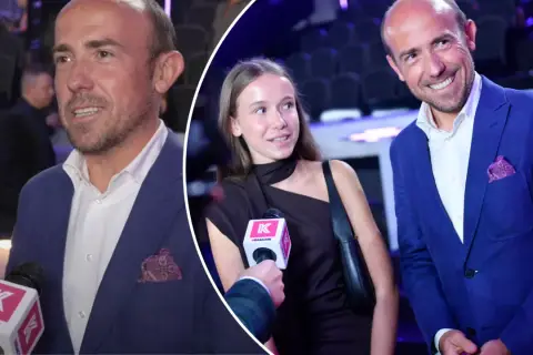 Borys Budka z córką na ściance. Mężczyzna w niebieskiej marynarce, dziewczyna w czarnej sukience.