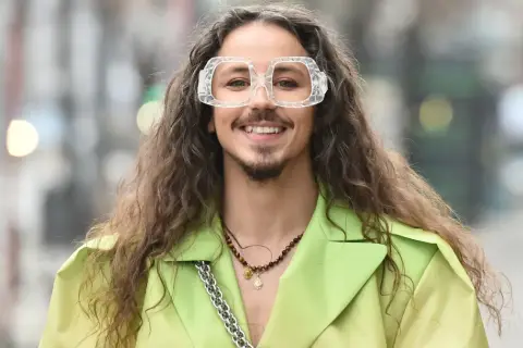 Uśmiechnięty Michał Szpak w limonkowym żakiecie i transparentnych okularach. Czy Michał Szpak jest gejem? To pytanie nurtuje wielu, ale jego styl i pewność siebie mówią same za siebie.