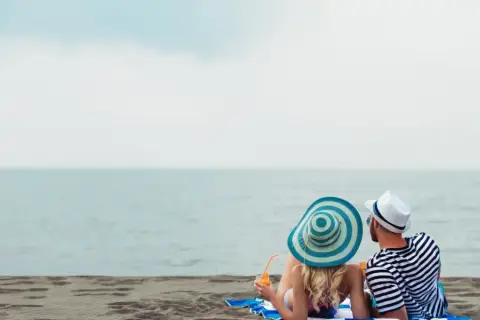 Para relaksu na plaży w Mielnie. Para w kapeluszach popija drinki, ciesząc się widokiem morza. Idealne mielno atrakcje dla dorosłych.