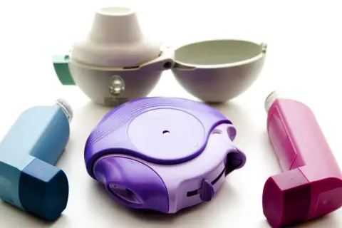 Drei Inhalatoren in Lila, Blau und Pink, sowie ein offener weißer Inhalator. Ein Beispiel für Medikamente wie Spiriva.