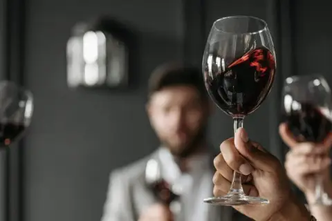 Verre de vin rouge, parfait pour accompagner un foie gras. Des mains lèvent des verres pour un toast.