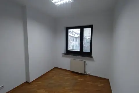Puste pomieszczenie z drewnianą podłogą i oknem. Zastanawiasz się, ile trwa malowanie mieszkania?