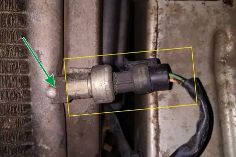Czujnik temperatury w Renault Kangoo znajduje się przy chłodnicy klimatyzacji. Strzałka wskazuje jego lokalizację.