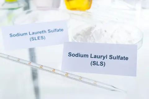 W laboratorium białe proszki: Sodium Laureth Sulfate (SLES) i Sodium Lauryl Sulfate (SLS). Pipeta z podziałką leży obok.