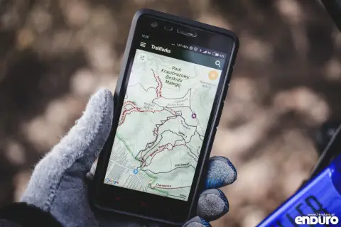 Rękawiczka trzyma smartfon z mapą szlaków rowerowych w Beskidzie Małym. To darmowa aplikacja do jazdy na rowerze, idealna na wyprawę.