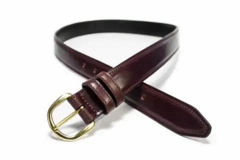 Ceinture élégante en cuir cordovan bordeaux avec boucle dorée, un accessoire intemporel pour parfaire votre tenue.